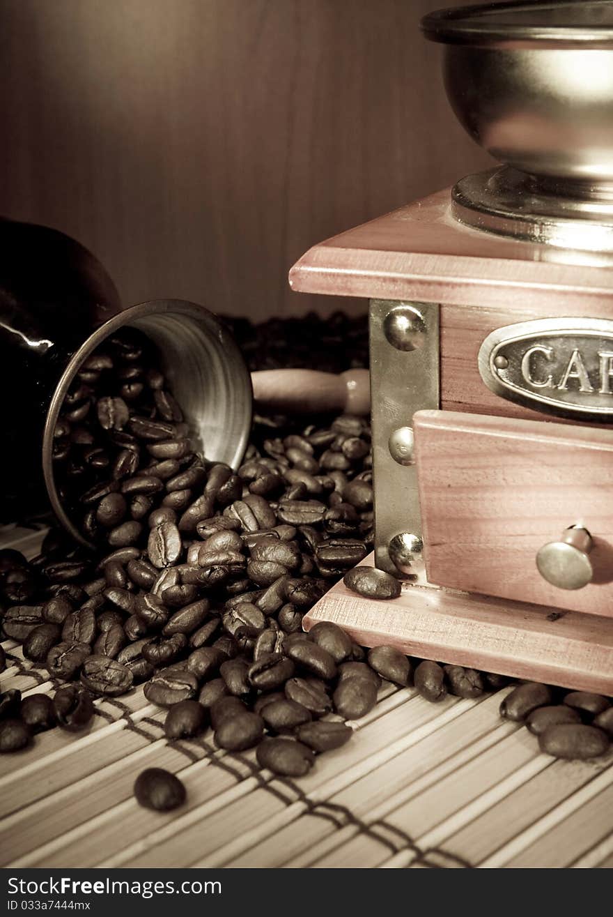 Coffee beans, copper pot and grinder on sacking