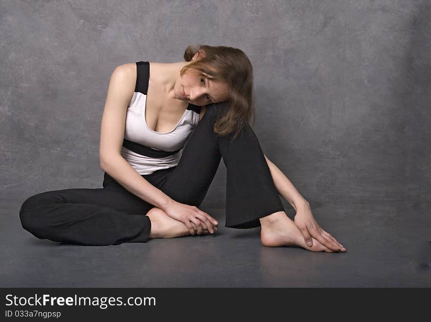 Sad woman sitting on a floor near concrete wall, studio shot. Sad woman sitting on a floor near concrete wall, studio shot