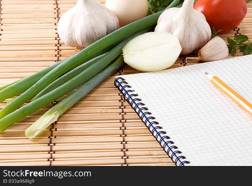 Notebook, Garlic, Tomato And Onion On Straw