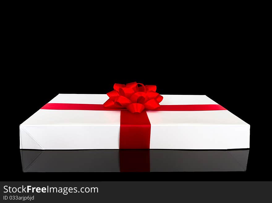 Gift box with red ribbon and bow isolated on black