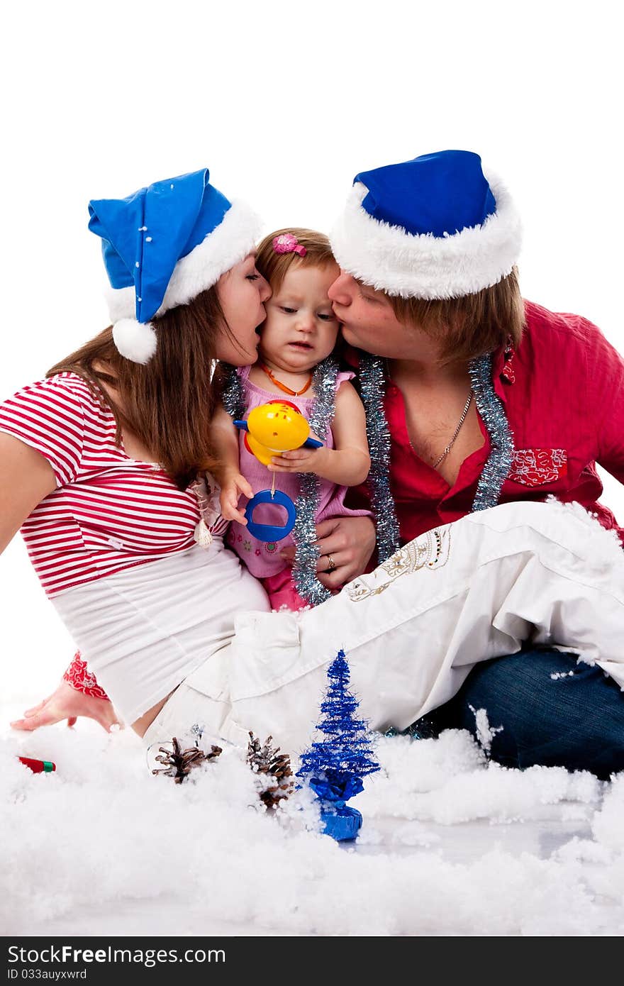 Parents in Santa's hat kissing their child in artificial snow isolated on white