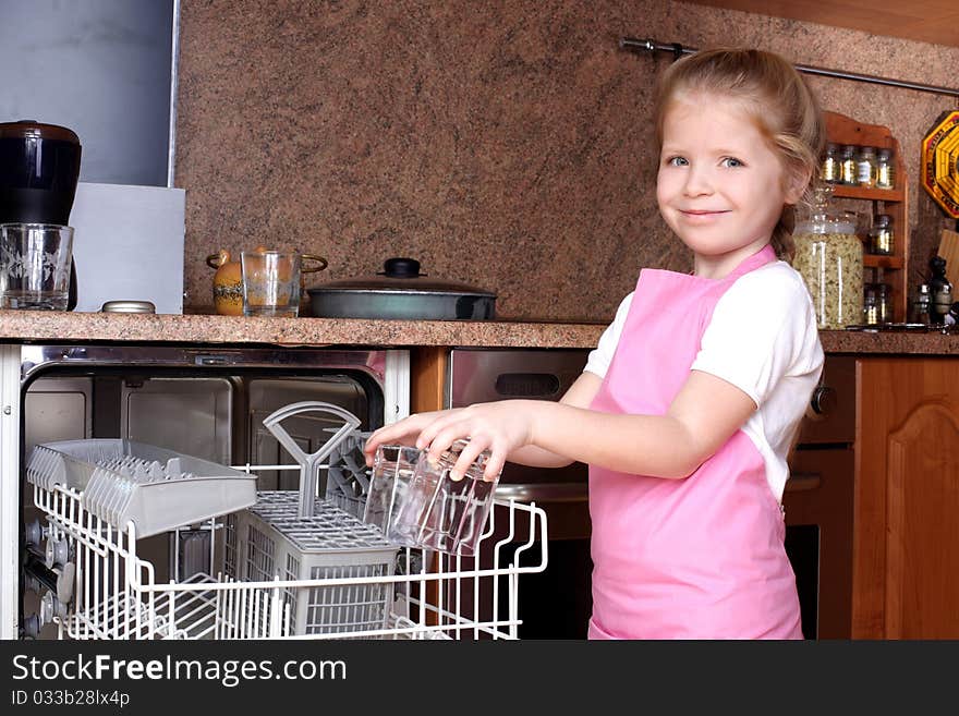 Little girl taken clear glass from dishwasher in the kitchen. Little girl taken clear glass from dishwasher in the kitchen