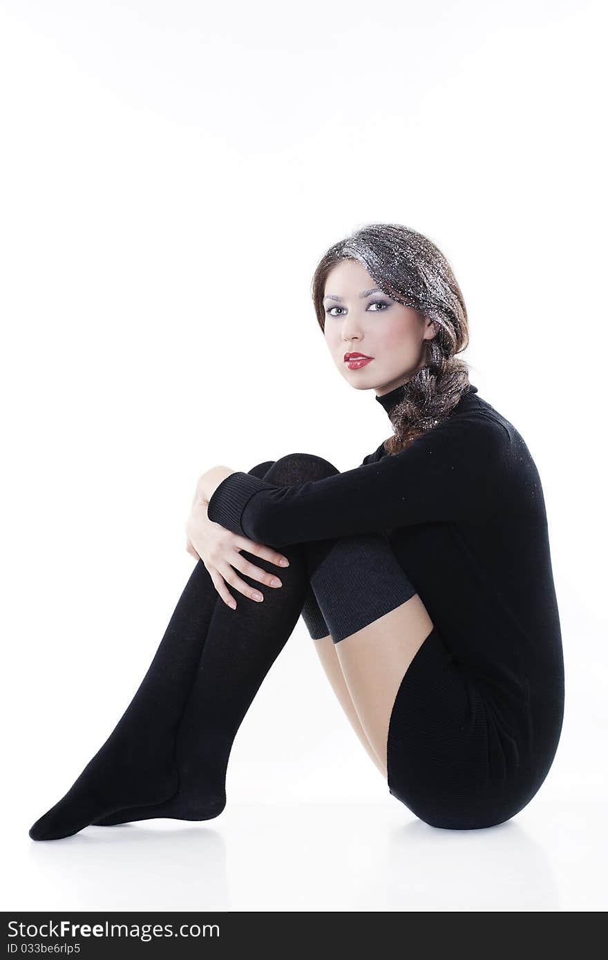 Fashion model wearing winter clothes with snow on her hair posing in studio