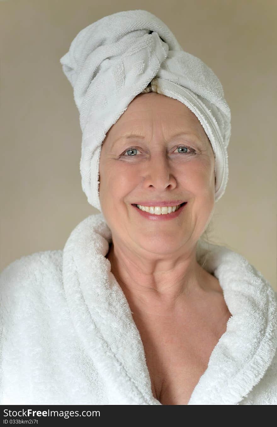 Color portrait photo of a Happy woman with towel wrapped around her head.