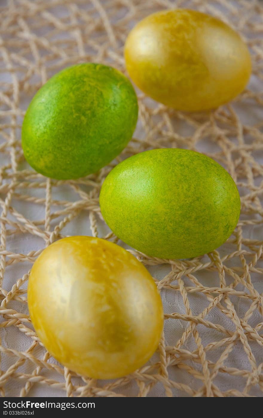 Green and yellow easter eggs on straw placemat