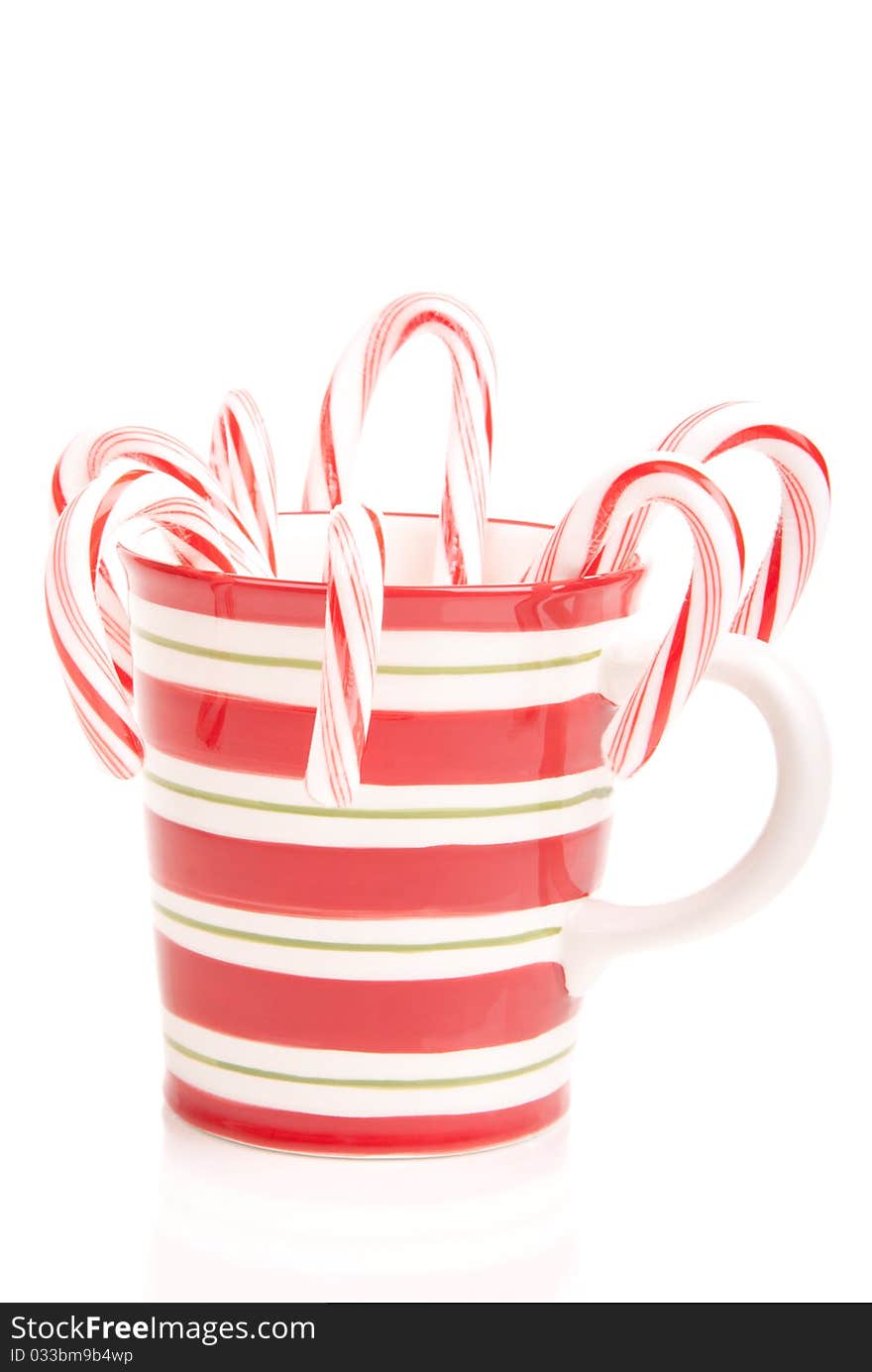 Christmas and new year mug full of sweet papermint candy canes with red and green stripes isolated on a white background. Christmas and new year mug full of sweet papermint candy canes with red and green stripes isolated on a white background