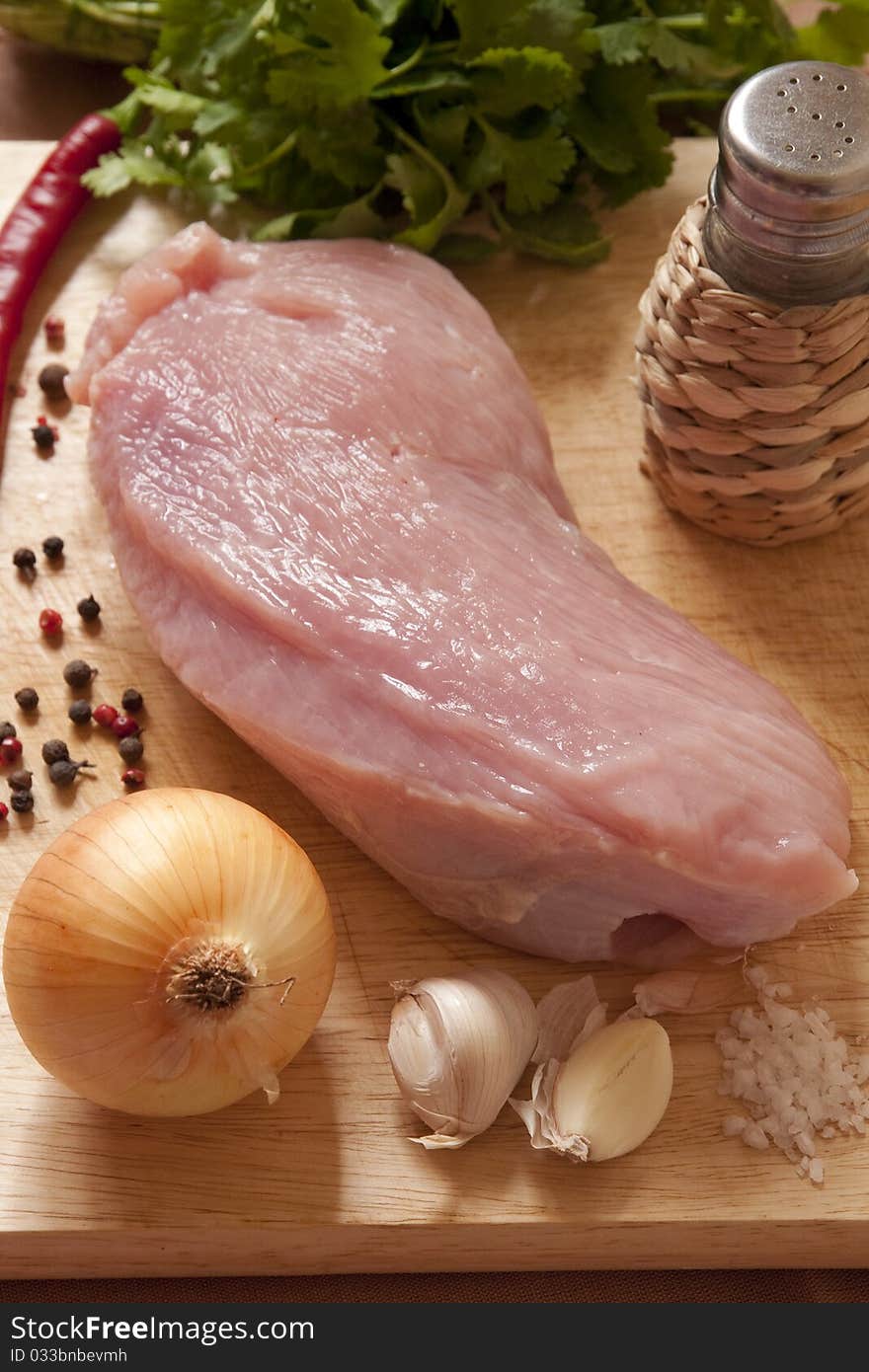 Raw meat, onion, garlic and spices on wooden board