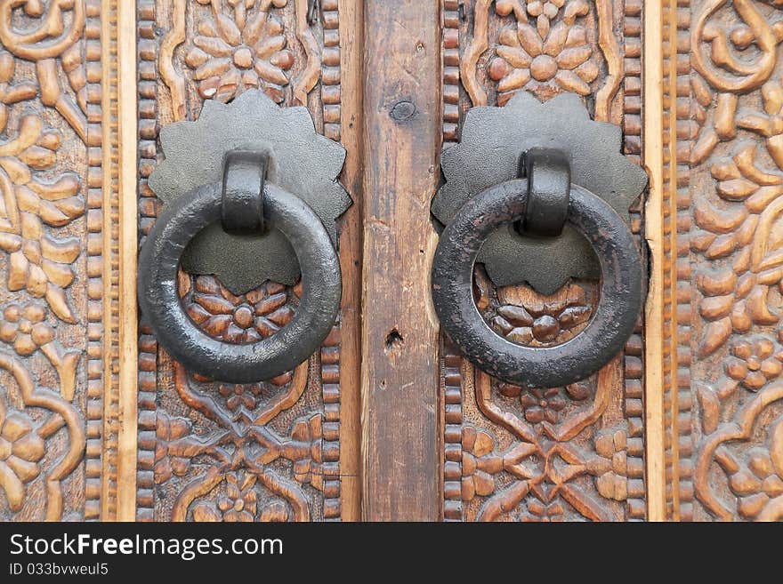 Wrought iron door handles on ornate wooden door