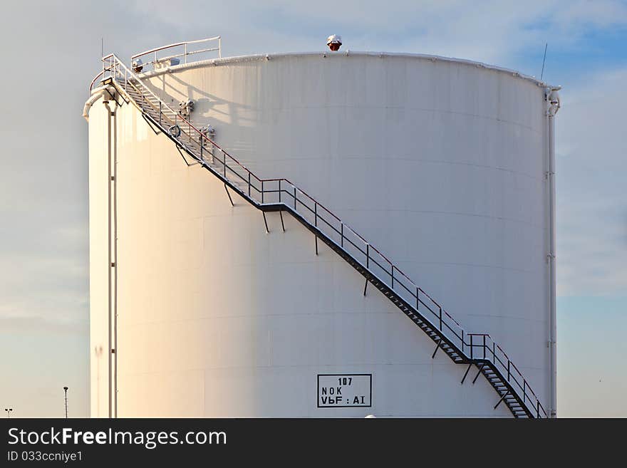 White tanks in tank farm with iron staircase in snow. White tanks in tank farm with iron staircase in snow