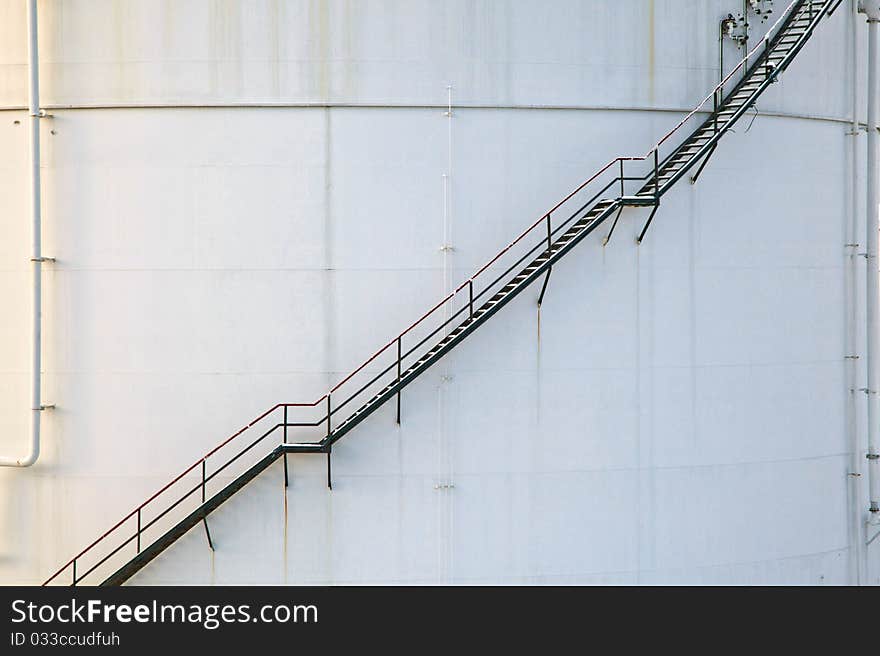 White tanks in tank farm with iron staircase in snow. White tanks in tank farm with iron staircase in snow