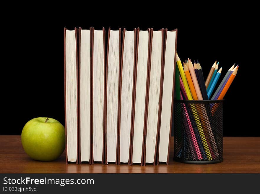 Stack of books and apple on a wooden table still life