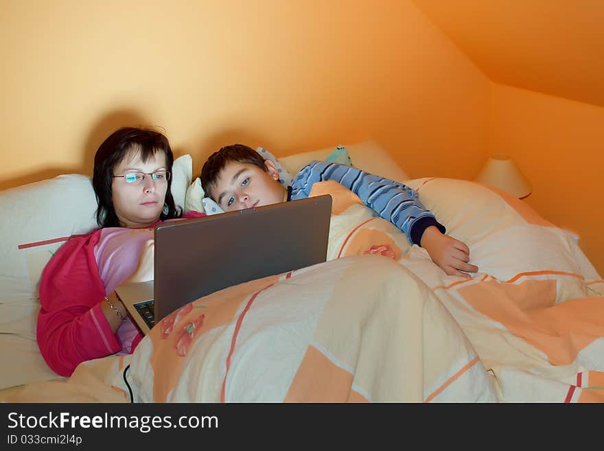 Portrait of a mother and her son using laptop while lying on the bed at home