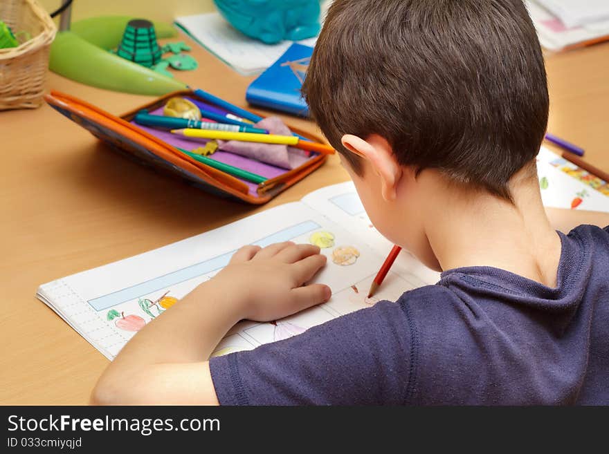 Boy doing homework with color pencil, painting fruits. Boy doing homework with color pencil, painting fruits