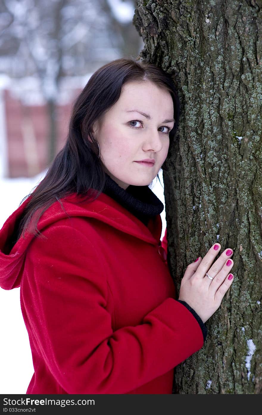 Girl in the red coat leaning on tree. Girl in the red coat leaning on tree