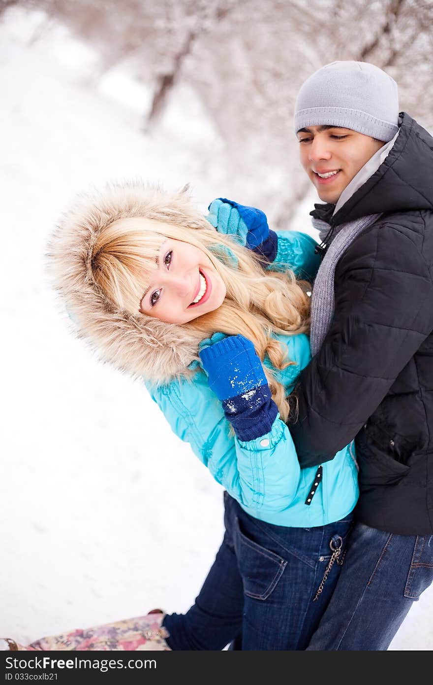 Happy young beautiful couple having a walk in winter park (focus on the woman). Happy young beautiful couple having a walk in winter park (focus on the woman)