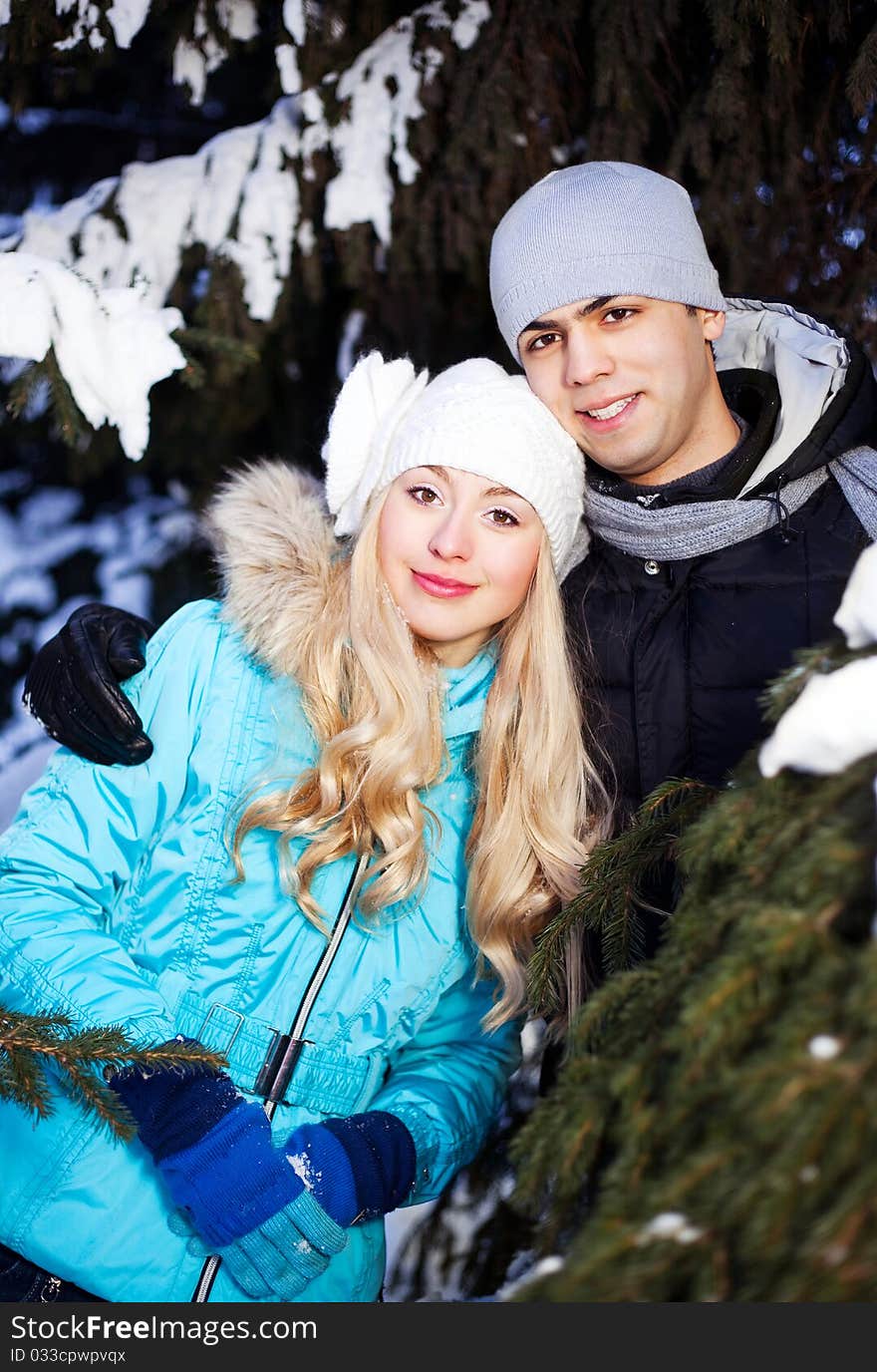 Happy young beautiful couple having a walk in winter park (focus on the girl). Happy young beautiful couple having a walk in winter park (focus on the girl)