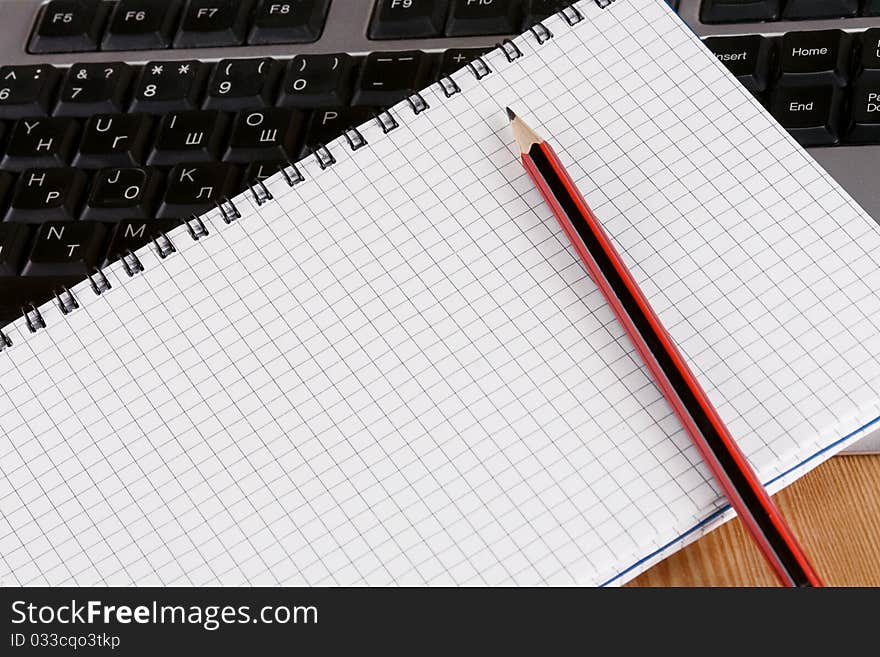 Pencil and notebook on computer keyboard. Pencil and notebook on computer keyboard