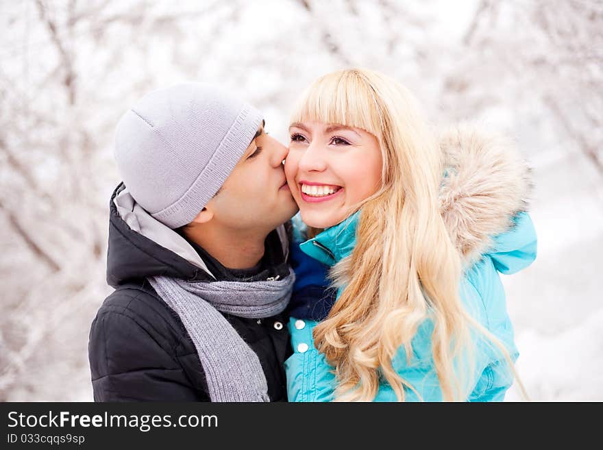 Happy young beautiful couple having a walk in winter park (focus on the woman). Happy young beautiful couple having a walk in winter park (focus on the woman)