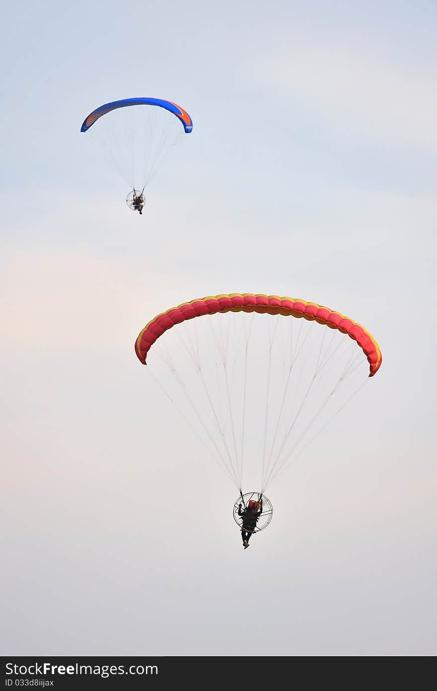 Two paramotors flying against blue sky