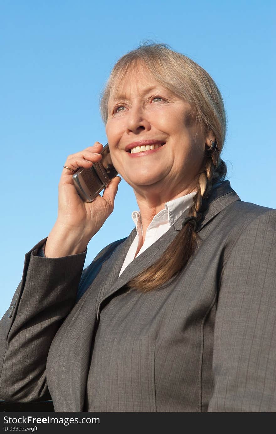 Happy mature businesswoman using cellphone.