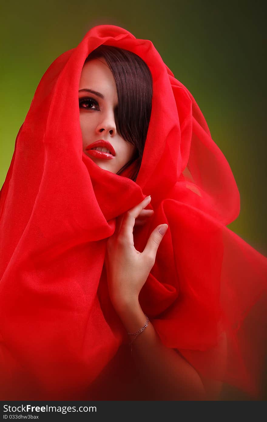 Wrapped in scarlet cloth face of a beautiful young girl with a glamorous make-up, where the bright red lips. Wrapped in scarlet cloth face of a beautiful young girl with a glamorous make-up, where the bright red lips