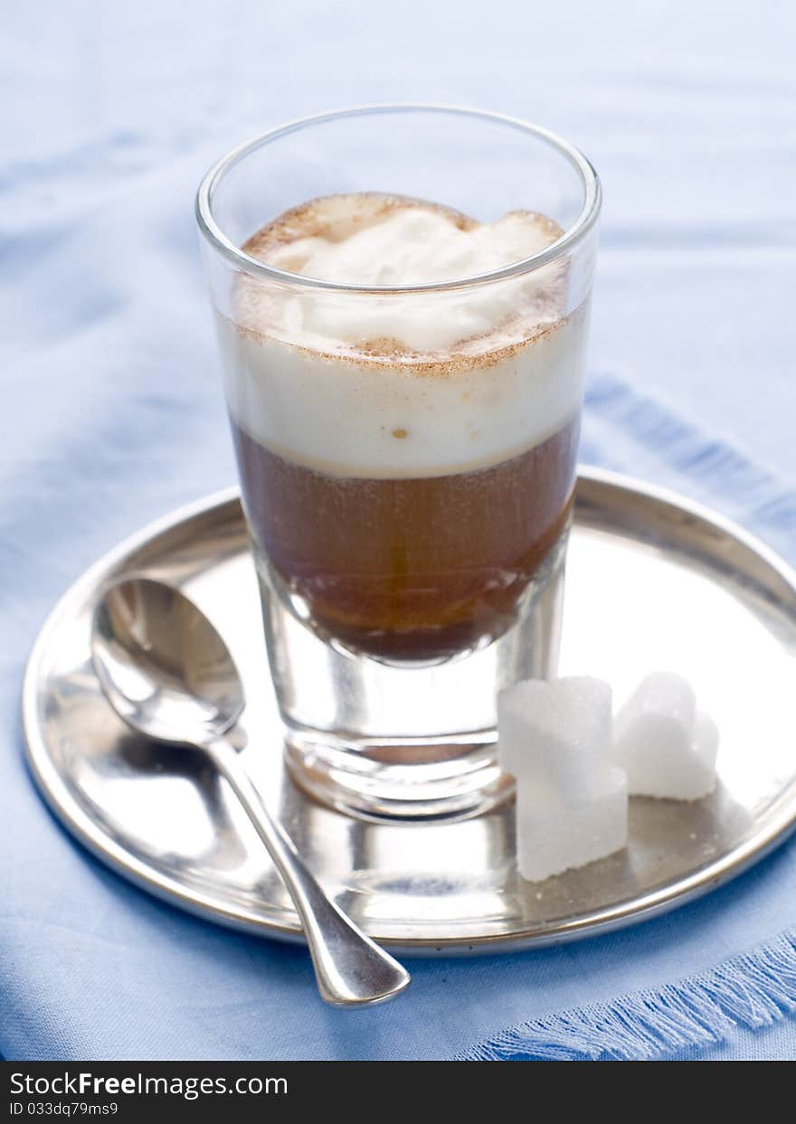 Cafe Latte in glass with spoon and sugar on plate. Cafe Latte in glass with spoon and sugar on plate