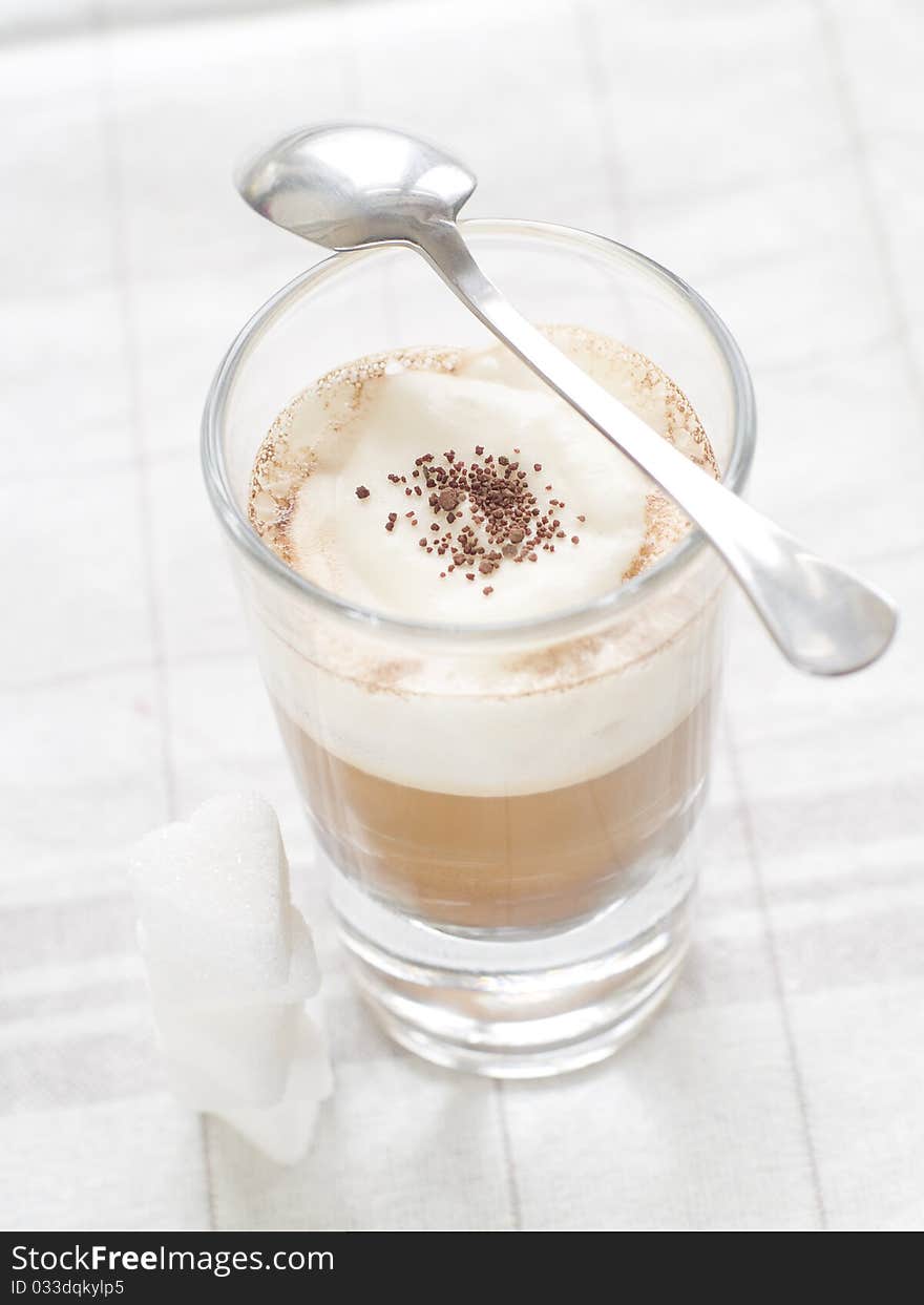 Cafe Latte in glass with spoon and sugar on plate. Cafe Latte in glass with spoon and sugar on plate