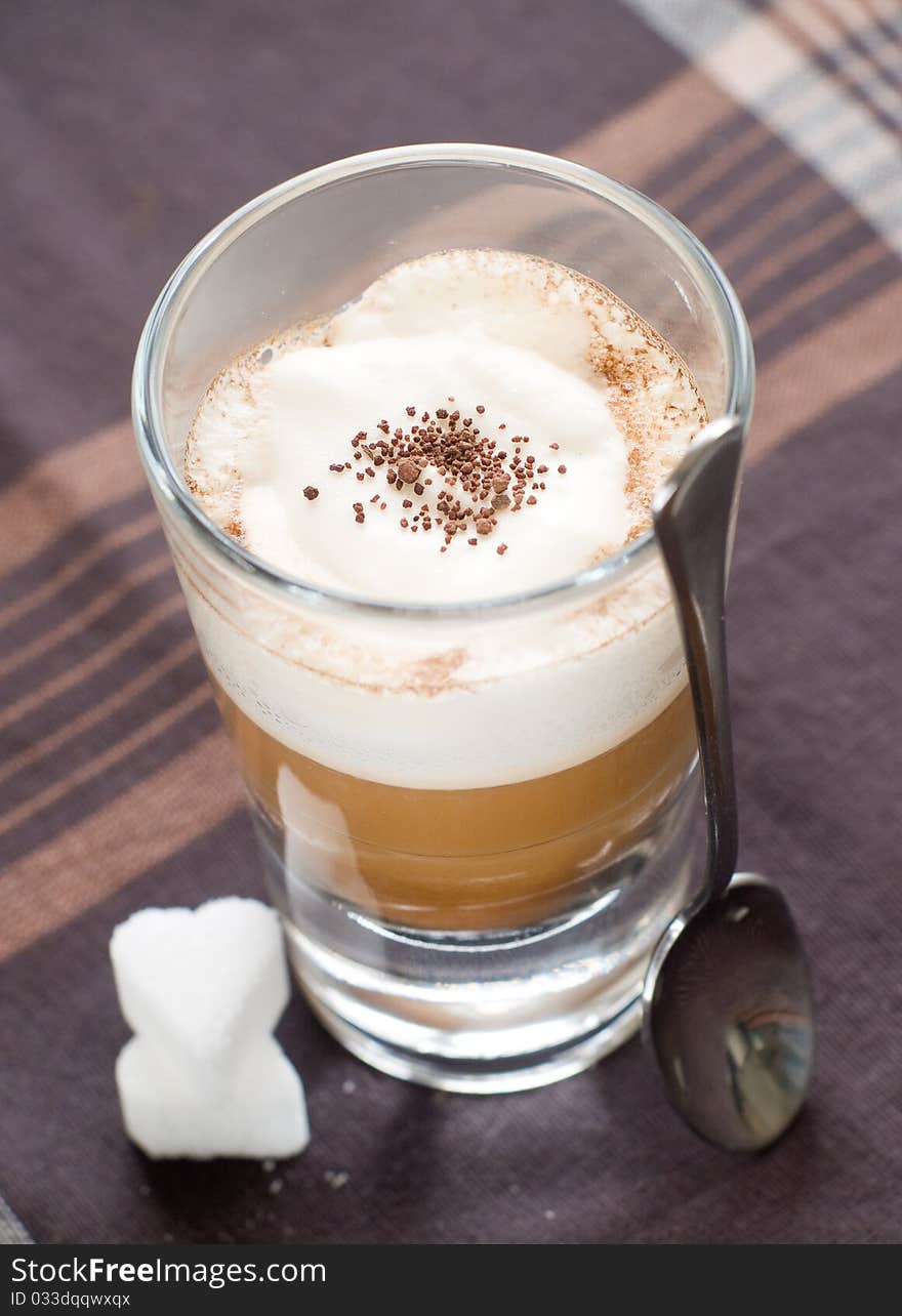 Cafe Latte in glass with spoon and sugar on plate. Cafe Latte in glass with spoon and sugar on plate