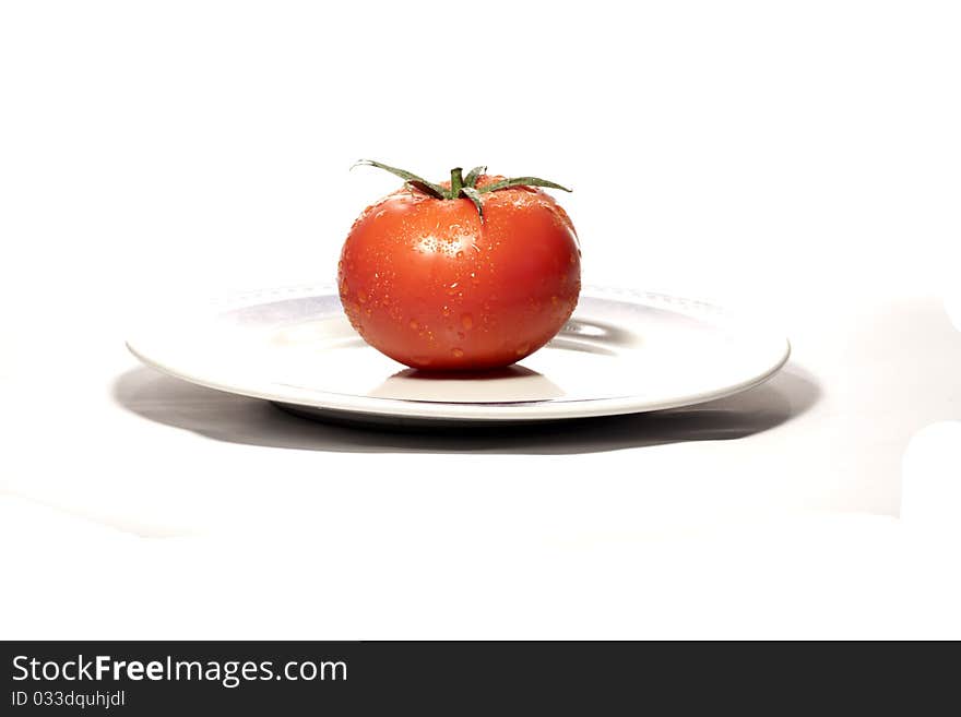 Close view detail of a red tomatoe on a plate isolated on a white background.