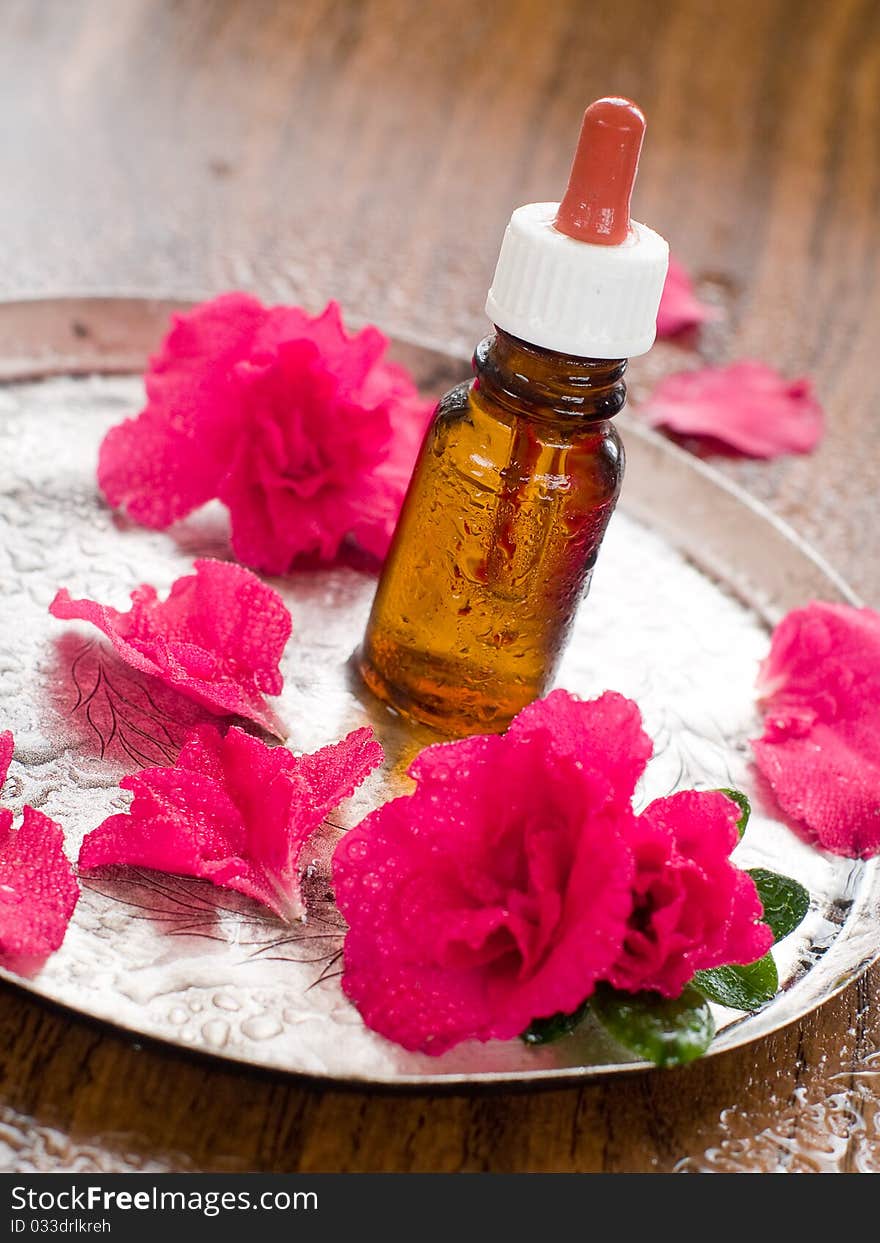 Essential oil bottle with flower and petal in background