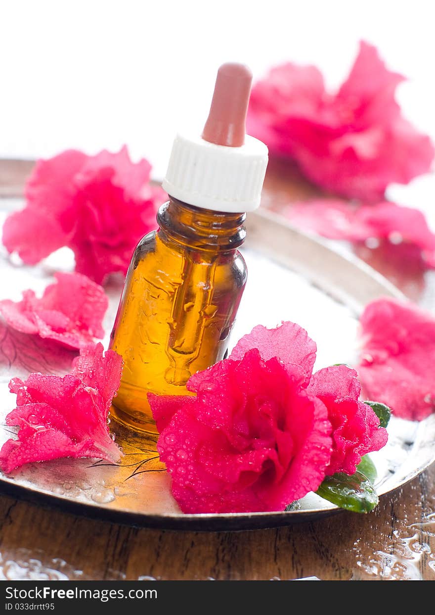 Essential oil bottle with flower and petal in background