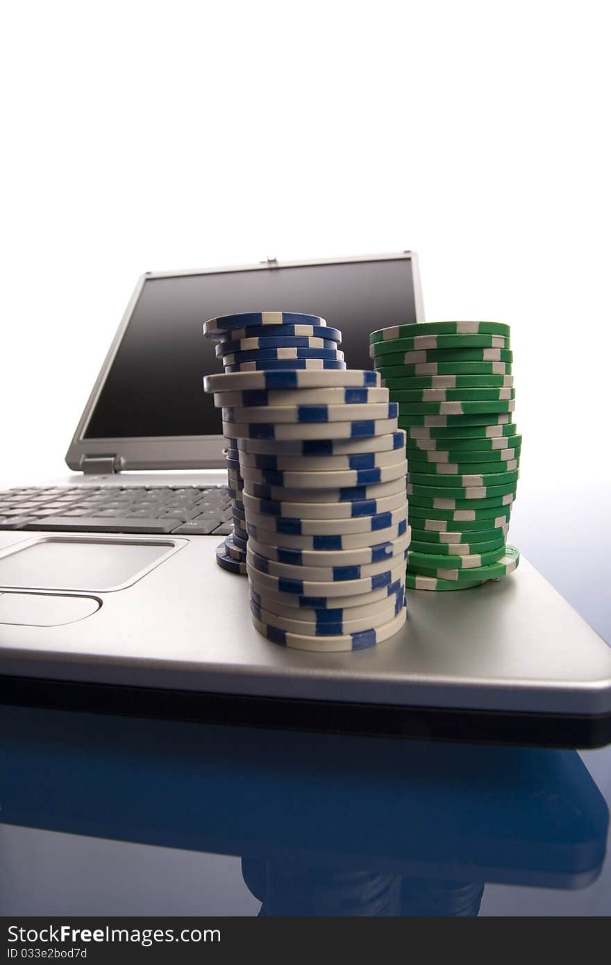 Multi - colored gambling chips and laptop on blue background. Multi - colored gambling chips and laptop on blue background