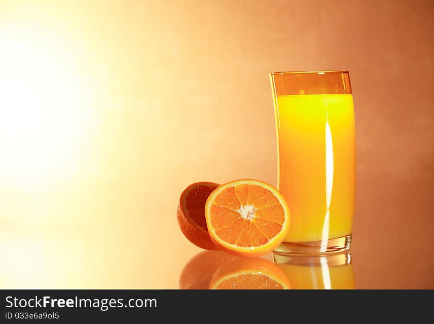 Sliced oranges near glass of orange juice on gradient background with reverberation