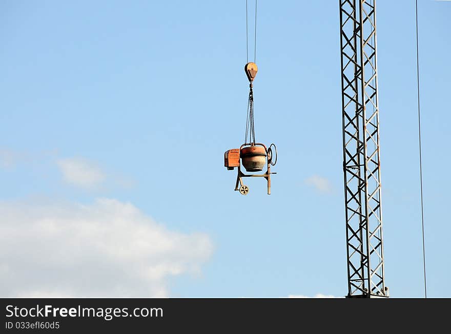 Cement mixer hanging from a crane at a construction site. Cement mixer hanging from a crane at a construction site