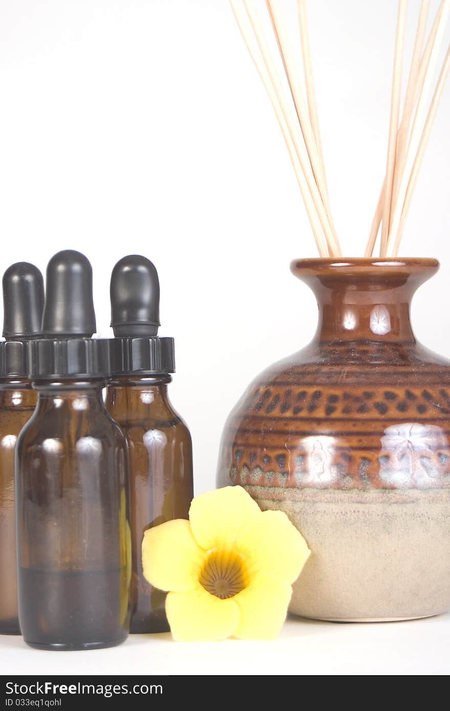 Three aromatherapy brown bottles with eyedroppers and yellow flower and scented reeds. Three aromatherapy brown bottles with eyedroppers and yellow flower and scented reeds