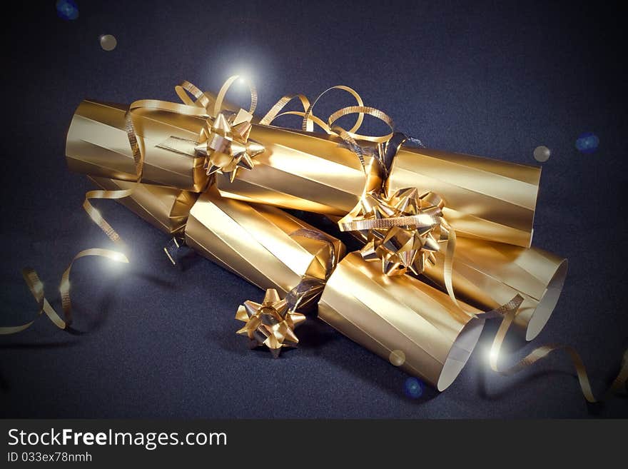 A close up of three sparkly golden crackers on a blue background. A close up of three sparkly golden crackers on a blue background