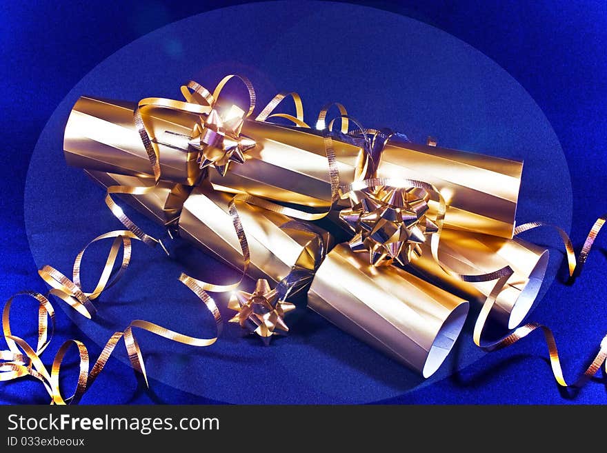 A close up of three sparkly golden crackers on a  blue background. A close up of three sparkly golden crackers on a  blue background