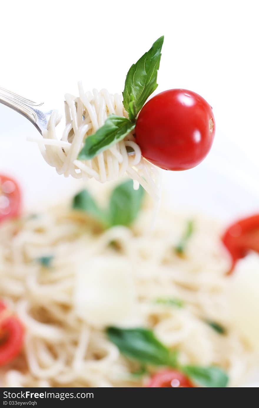 Spaghetti, basil and tomato on fork