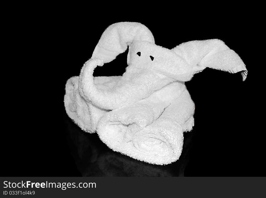 White towel folded into an origami elephant isolated on a black background with a reflection. White towel folded into an origami elephant isolated on a black background with a reflection