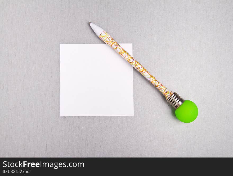 Funny colored pen with bright green light bulb and a blank paper. Funny colored pen with bright green light bulb and a blank paper