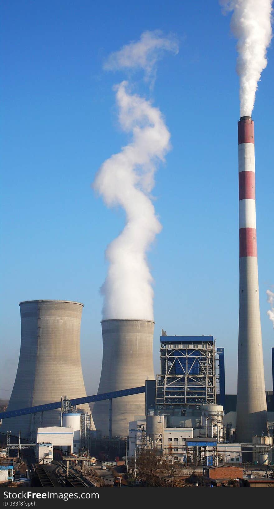 Scenery of water towers and chimney with steam in a heat power plant