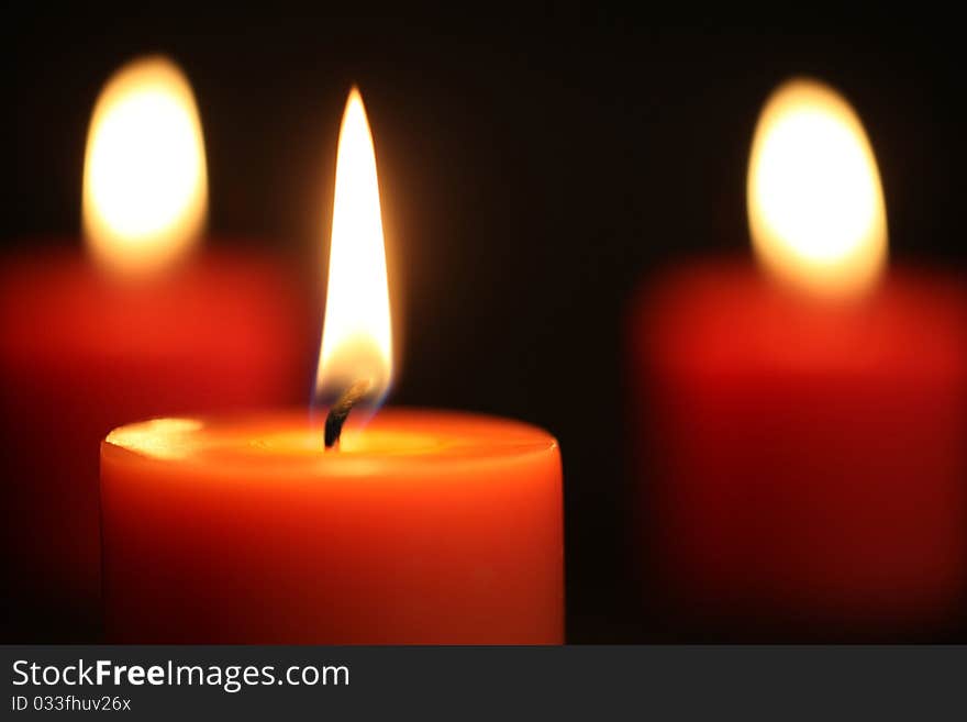 Close up of three Red candles lit against black