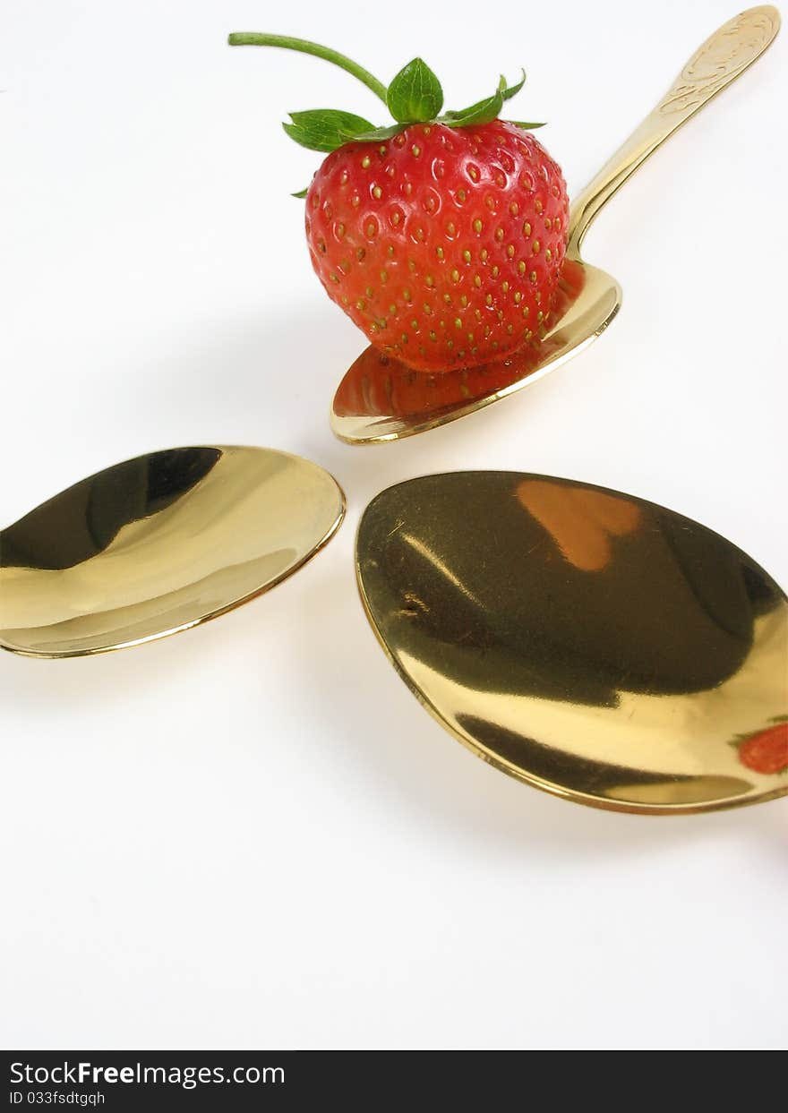 Abstract. Three gold spoon and single strawberry. Abstract. Three gold spoon and single strawberry