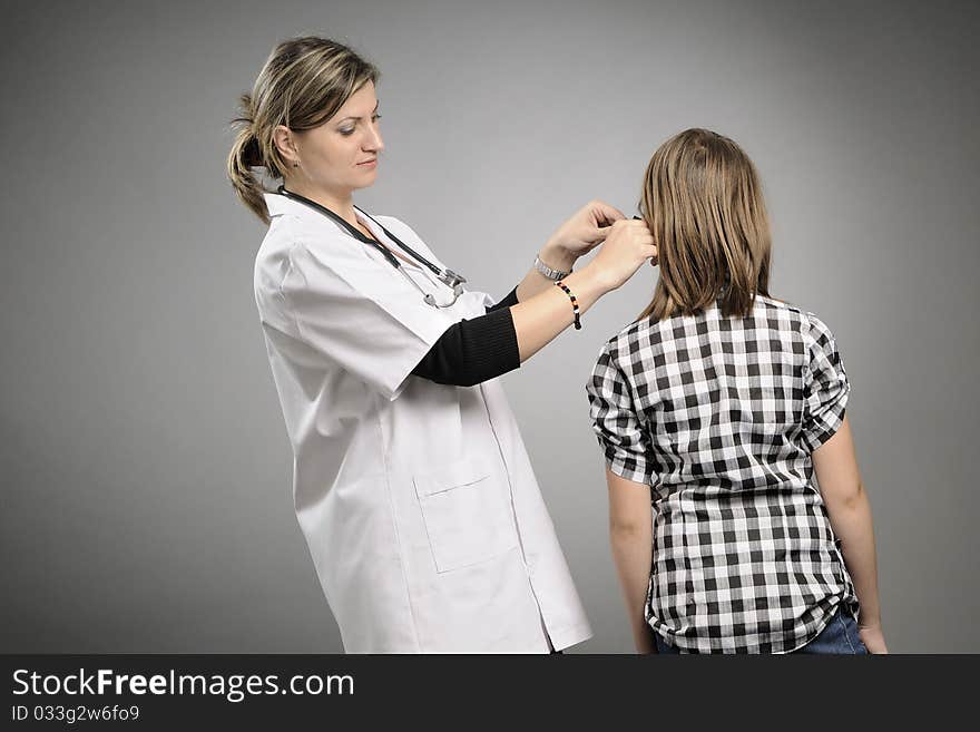 Young doctor examining with tool girl ear. Young doctor examining with tool girl ear