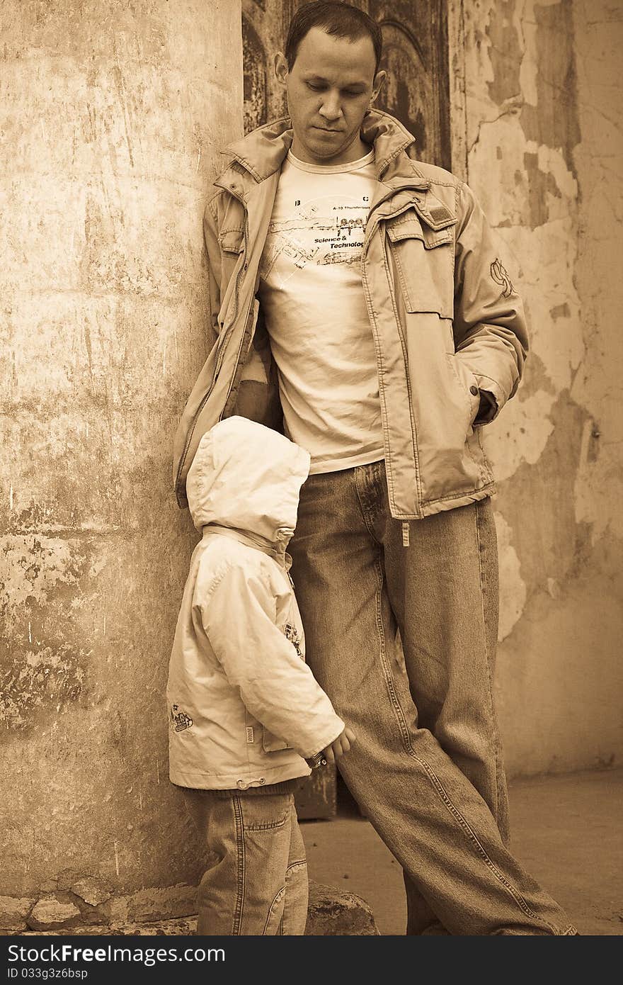 Man leaning against the column of a shabby building, child on the foreground. Man leaning against the column of a shabby building, child on the foreground