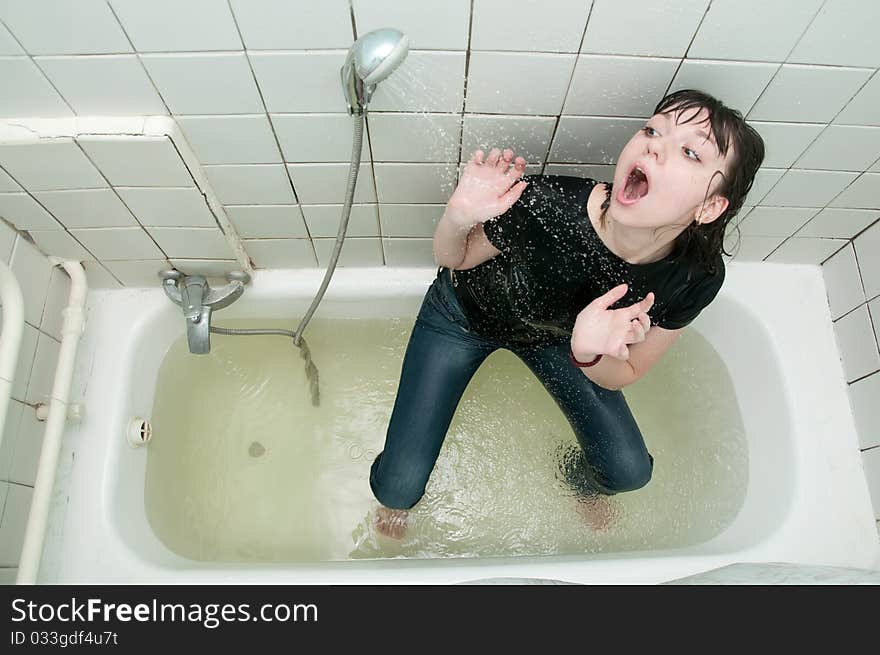 Girl in clothes in the bathroom under the shower. Girl in clothes in the bathroom under the shower