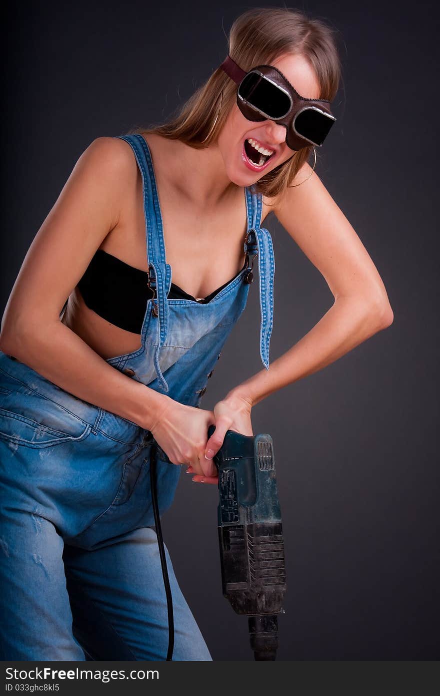 Girl with a drill in building overalls