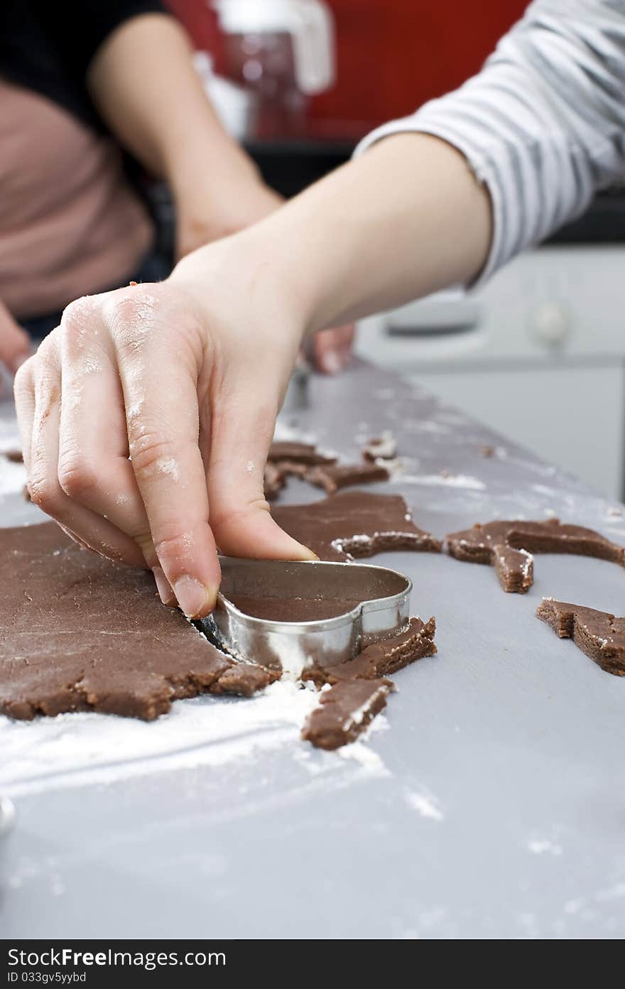 Close up of female hand with heart cookie cutter. Baking brown chocolate cookies. Close up of female hand with heart cookie cutter. Baking brown chocolate cookies.