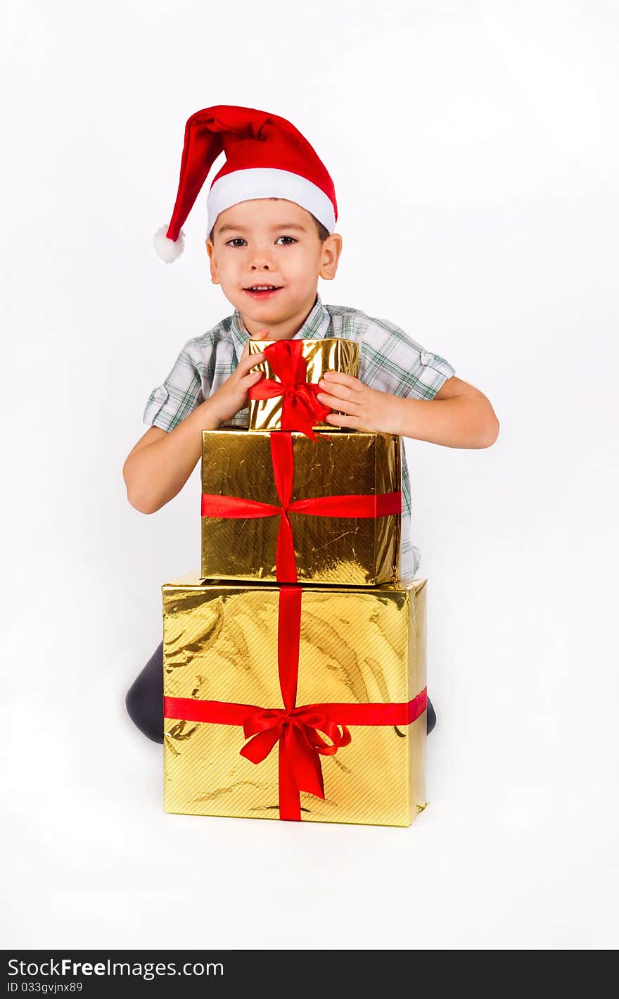 Little boy in Santa hat with a bunch of gifts