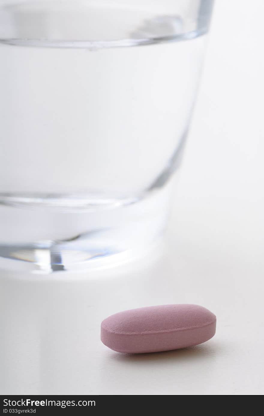 Pill next to a glass of water